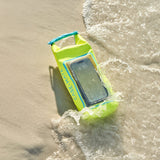 Phone in a yellow waterproof case on a sandy beach with waves.
#color_citrus splash
