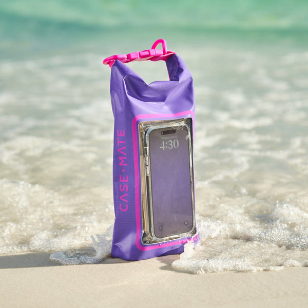 Purple and pink waterproof phone case with a phone inside, placed on a sandy beach with water in the background.
#color_purple paradise
