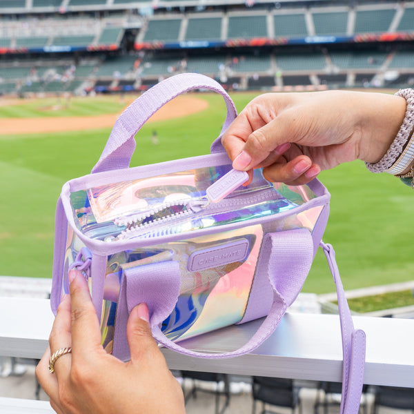 Woman unzipping top of iridescent stadium bag at a baseball game #color_iridescent