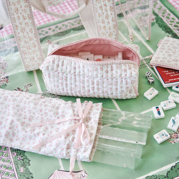 Floral-patterned pouches and game pieces on a green surface with a checkered border #color_quilted ditsy floral