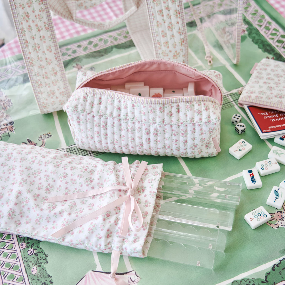 Floral-patterned pouches and game pieces on a green surface with a checkered border #color_quilted ditsy floral