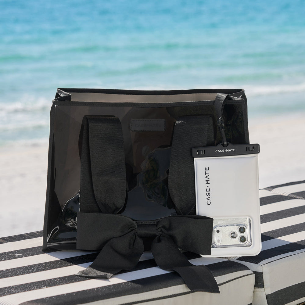 Black bag with a phone case on a striped towel by the beach