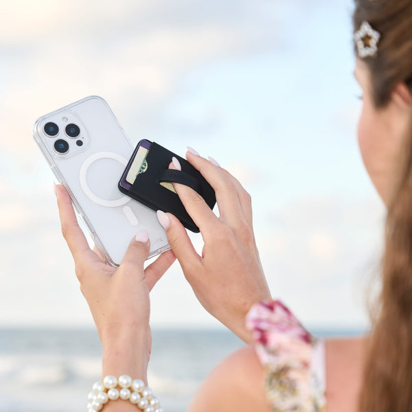 Person holding two smartphones with magnetic phone holders against a blurred outdoor background
#color_midnight black