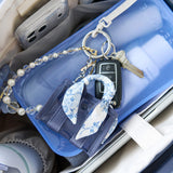 Keychain with a blue ribbon and pearl details on a car seat.
#color_something navy twilly