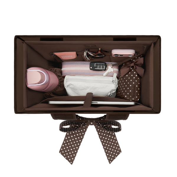 A brown organizer box shown from above, packed with travel accessories including a pink water bottle, a striped pouch, a white pouch, sunglasses, a pink case, and a polka-dot bag, on a white background.

#color_espresso