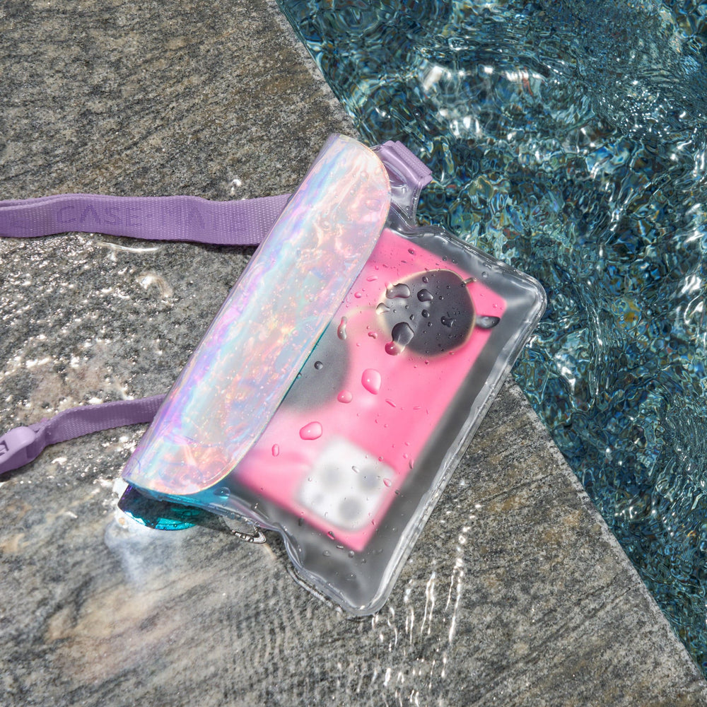 Pink phone case with purple strap on a stone surface near water