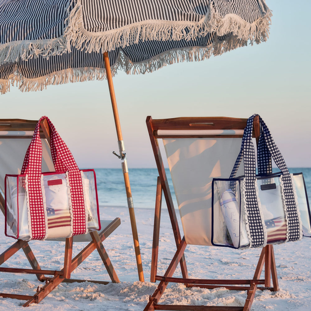 Beach scene with wooden chairs, striped umbrella, and beach bags on a sandy beach