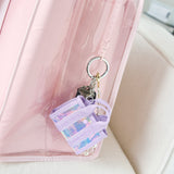 Purple keychain with colorful design attached to a pink bag on a white 
surface
#color_iridescent