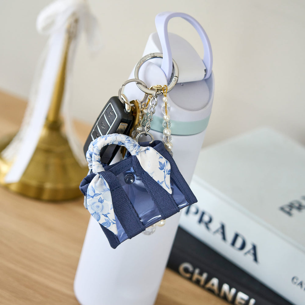 Keychain shaped like a blue handbag with floral patterns on a blurred background
#color_something navy twilly