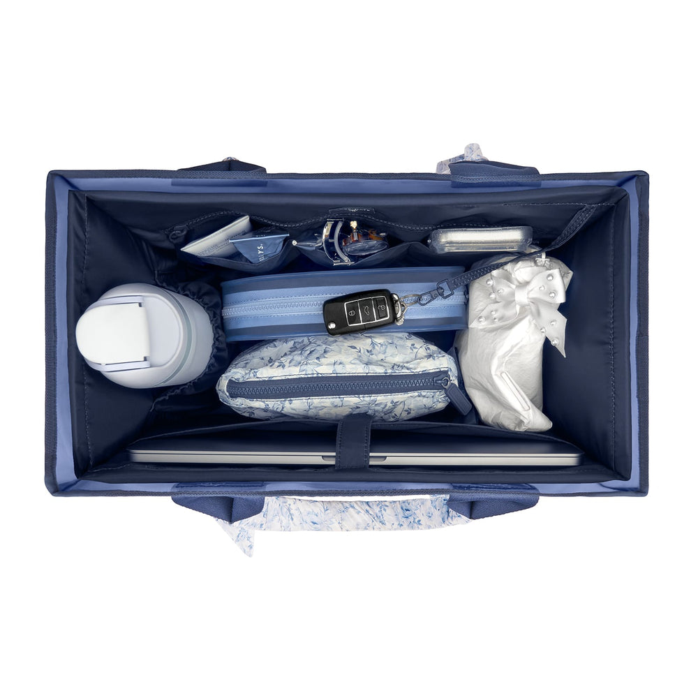 Top-down view of a navy blue organizer bag packed with travel accessories, including a patterned pouch, a water bottle, a car key fob, and a plastic bag, on a white background.

#color_navy