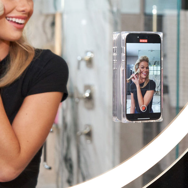 Smart mirror displaying a woman's reflection with a phone app interface.
#color_iridescent