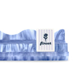 A white rectangular card or label with a blue flower illustration and the word 'flower' in script, standing upright on a blue marbled surface against a white background.
#color_carolina blue pearl