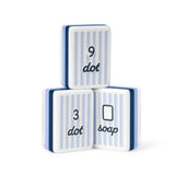Three white rectangular blocks with light blue vertical stripes and dark blue text, stacked in a pyramid on a white background. The top block reads '9 dot', the bottom left reads '3 dot', and the bottom right reads 'soap'.
#color_cabana stripe edition