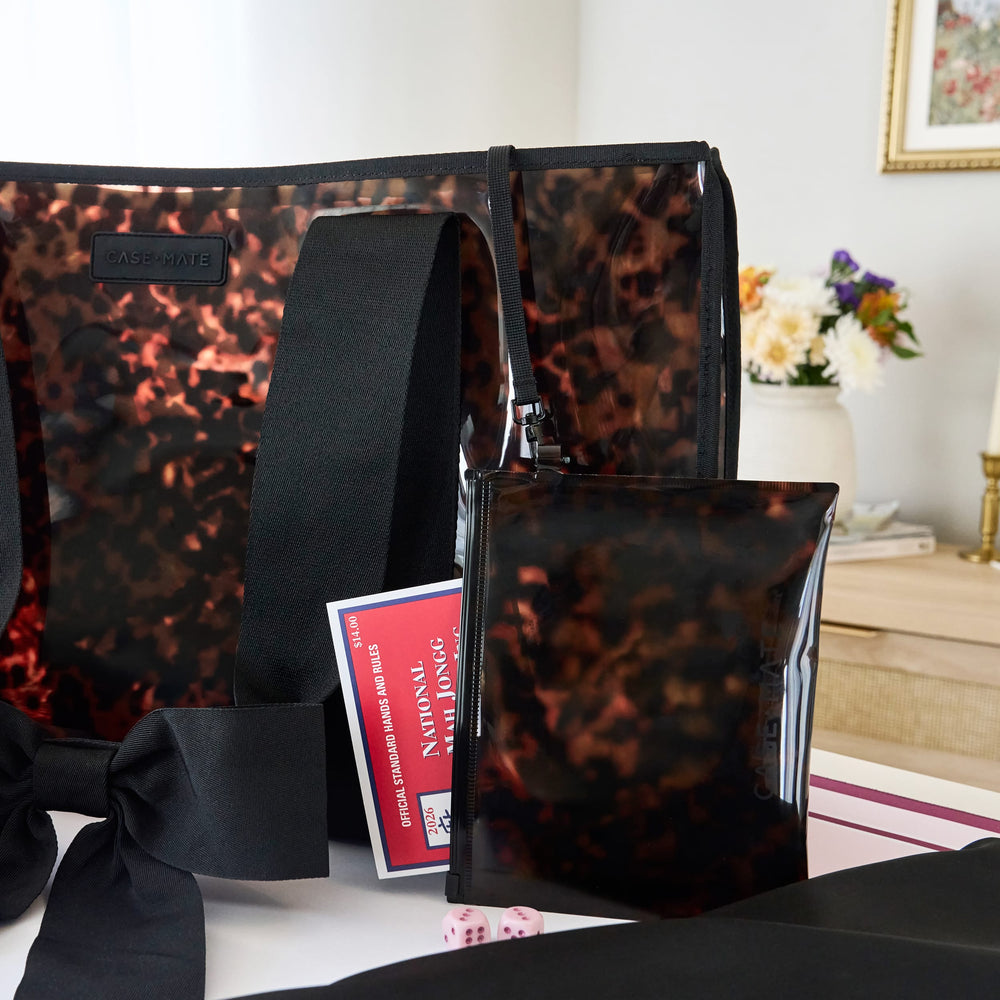 A clear tote bag with a black tortoiseshell pattern, black shoulder strap, and matching black pouch, displayed on a table with a mahjong card in a home interior setting.

#color_tortoiseshell bow