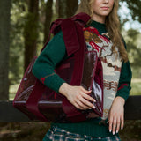 Woman in a holiday sweater outdoors ina. woodsy setting with a red velvet bow jelly tote bag. #color_holiday edition red velvet bow