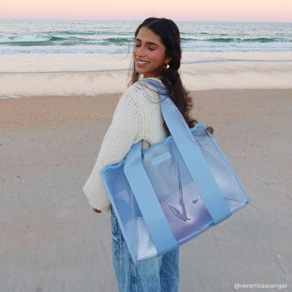 A woman on a beach showing off her jelly crotchet wave tote bag