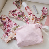 Floral swimsuit with pink pouch and skincare products on a light surface
#color_ballet pink bow