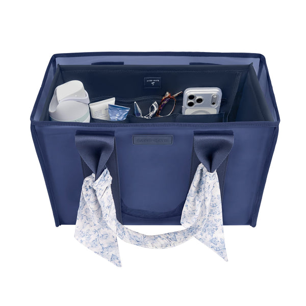 A navy blue fabric organizer bag with two handles, shown open to reveal storage compartments filled with travel accessories. The bag has a small 'LIVING LIFE' brand label on the front and a matching patterned scarf hanging from one of the handles against a plain white background.
#color_navy