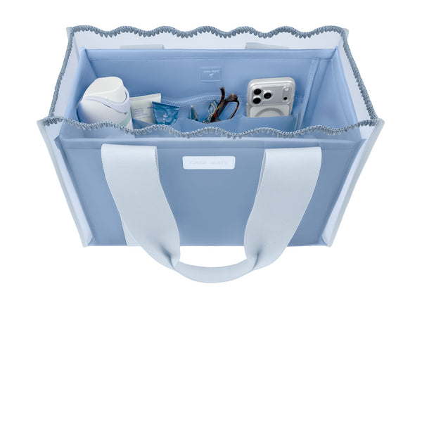 A light blue fabric storage tote bag with white handles, shown from a top-down view on a white background. The bag is filled with various small items, including a white bottle, a blue packet, and a white camera.

#color_carolina blue