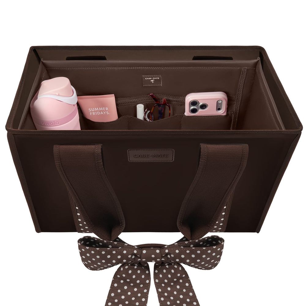 A brown fabric car organizer bag with a matching polka-dot bow, shown open to reveal interior pockets holding a pink bottle, mug, cord, and phone. The bag has a visible 'CASE-MATE' label and is photographed on a clean white background.

#color_espresso