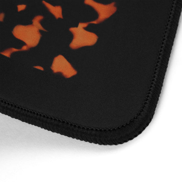 Close-up of a black mouse pad with an orange abstract flame or burn-effect graphic and black stitched border, shown on a white background.
#color_classic tortoiseshell