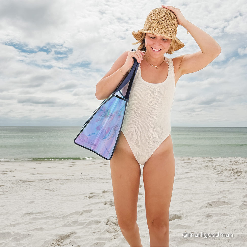 Woman wearing a swimsuit holding her hat down from blowing away on the beach 
#color_oxford navy iridescent