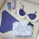 Blue floral pouch with purple bikini and accessories on a beige surface
#color_something navy bow