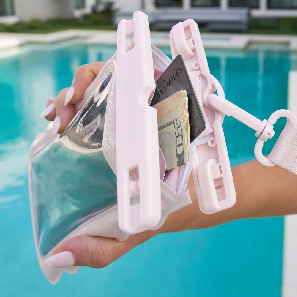 Hand holding a clear pouch with money clips against a pool background #color_ballet pink twinkle