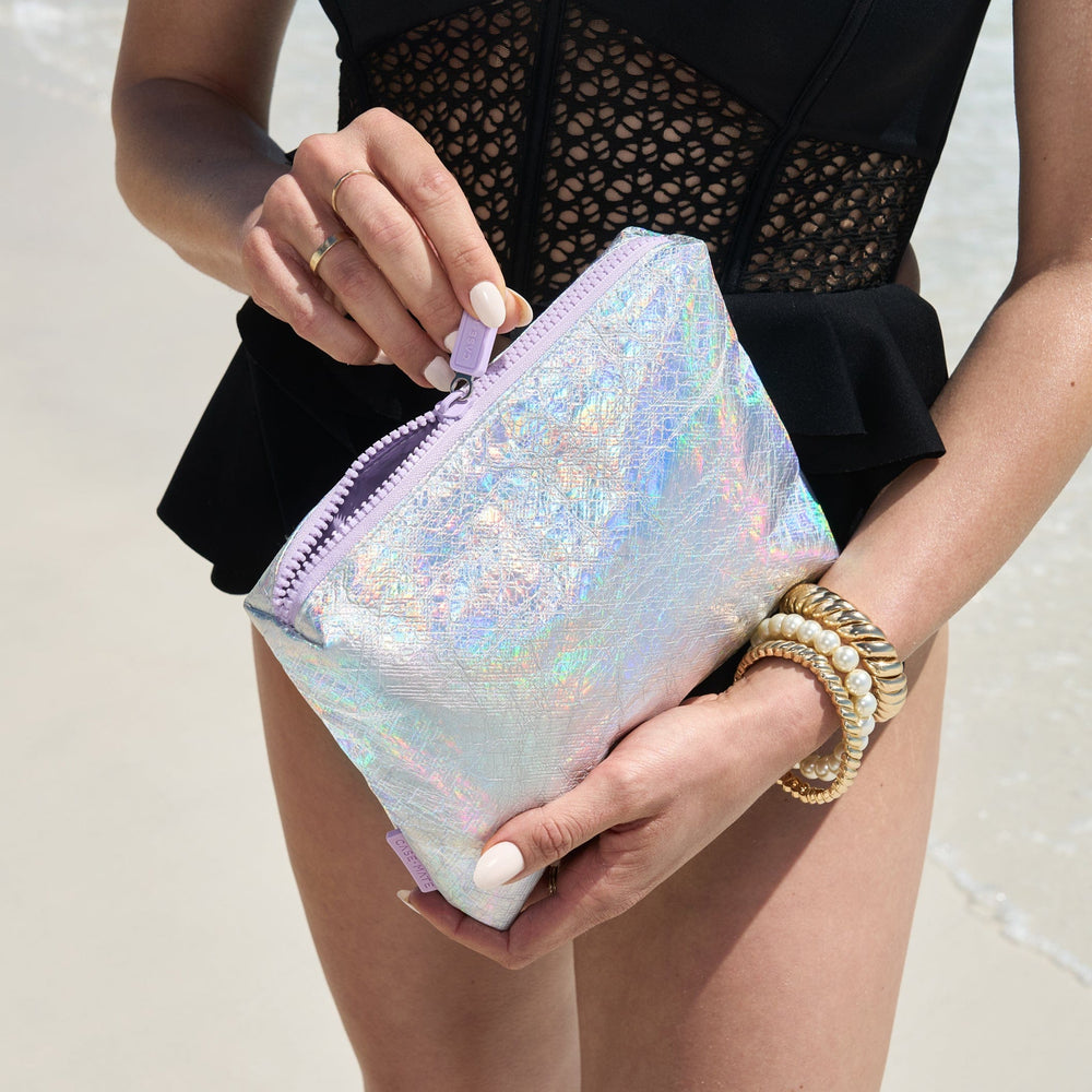 Person holding a iridescent clutch bag with a blurred background