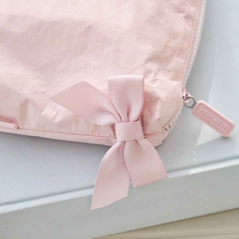 Pink pouch with a bow and a visible brand tag on a light gray background