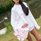 Woman holding a pink bag with a bow in a natural setting
