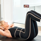 Woman exercising on a mat with a smartphone displaying an app above her head.
#color_stardust