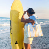 Woman holding a yellow surfboard on a beach with a clear sky
#color_cabana stripe bow