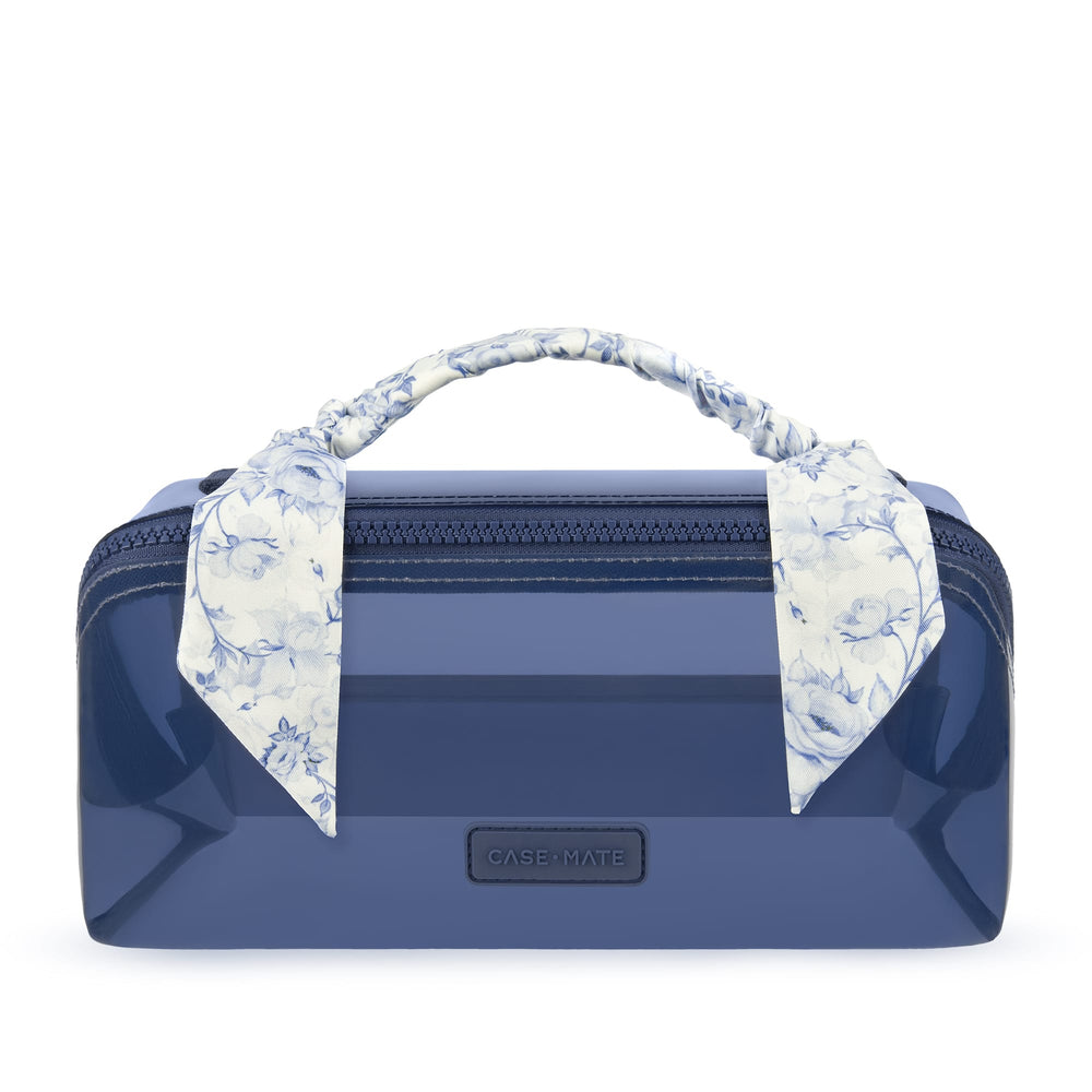 A glossy navy blue Case-Nate cosmetic case with a top zipper, a matching fabric handle, and a blue-and-white floral scarf tied to the handle, shown on a white background.
#color_something navy twilly