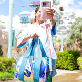 Person taking a selfie with a colorful bag and phone case at Disney Parks 
#color_emerald blue soap bubble®