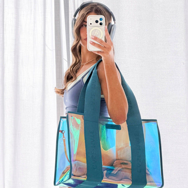 Person holding a transparent tote bag with colorful design, wearing headphones and taking a mirror selfie.
#color_emerald blue iridescent