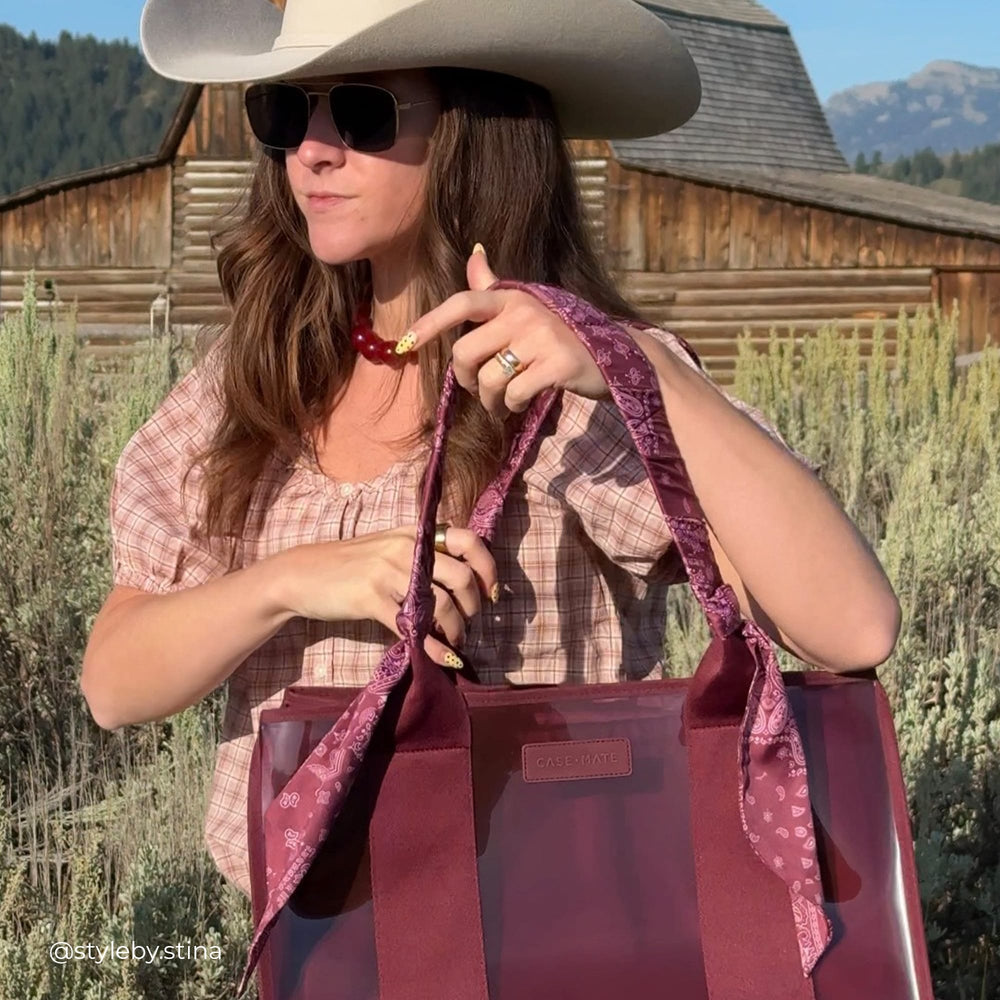 Woman on a ranch with a cowboy hat on and Jelly tote on her shoulder 
#color_mulberry twilly