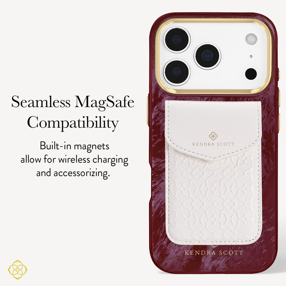 A Kendra Scott phone case with a deep burgundy marbled exterior, a gold-toned camera ring, and a white textured magnetic card holder pocket on the back. The left side of the image features text explaining 'Seamless MagSafe Compatibility' and 'Built-in magnets allow for wireless charging and accessorizing.
#color_cherry lacquer pearl