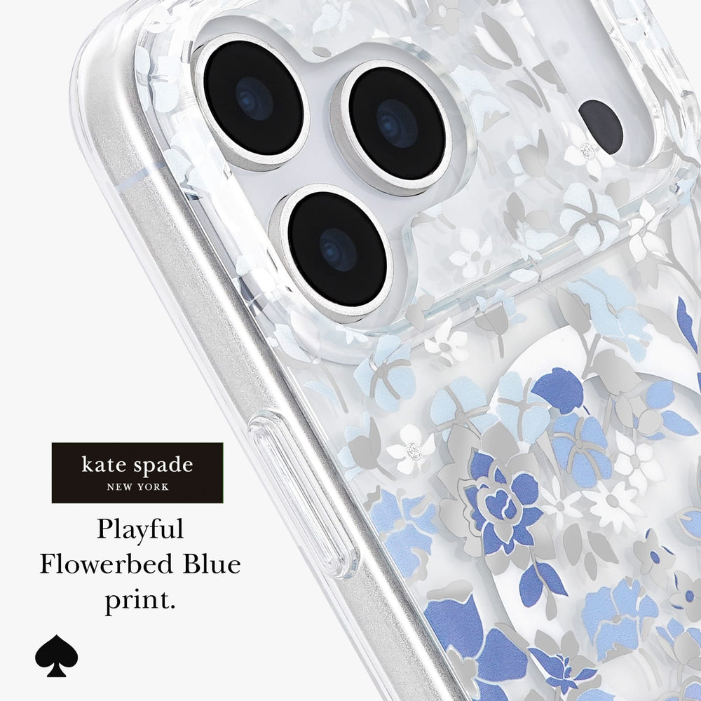 A close-up of a clear phone case with a blue and white floral print, shown on a phone. The text on the left reads 'kate spade NEW YORK Playful Flowerbed Blue print.
#color_flowerbed blue