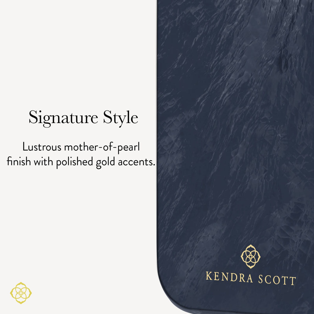 A close-up of a Kendra Scott product with a dark navy blue marbled finish and polished gold accents, including the brand name and logo. Text on the left reads 'Signature Style' and describes the lustrous mother-of-pearl finish with gold accents.