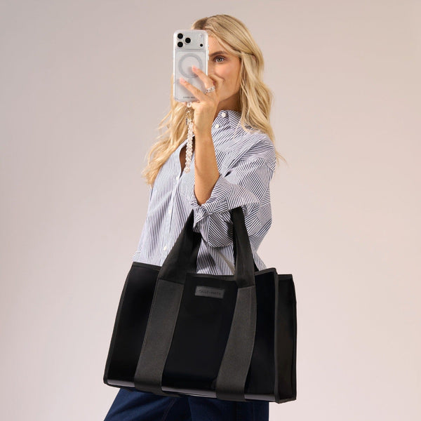 Woman holding a black tote bag with a neutral background
#color_midnight black