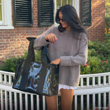 Woman holding a black and blue handbag outdoors with a brick building in the background
#color_midnight black bow