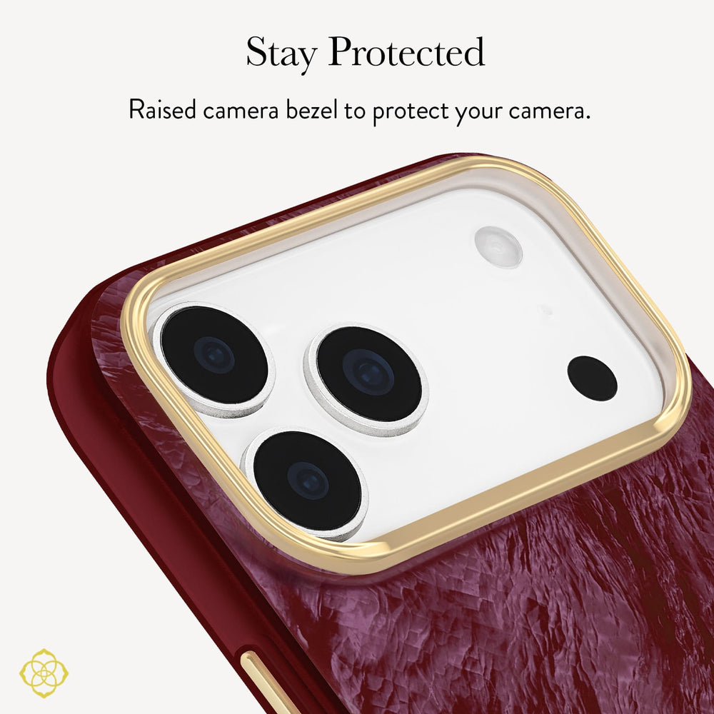 Close-up of a phone case with a textured deep red back and a raised gold camera bezel, with text above reading 'Stay Protected' and 'Raised bezel to protect your camera.'. 
#color_cherry lacquer pearl