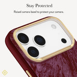 Close-up of a phone case with a textured deep red back and a raised gold camera bezel, with text above reading 'Stay Protected' and 'Raised bezel to protect your camera.'. 
#color_cherry lacquer pearl