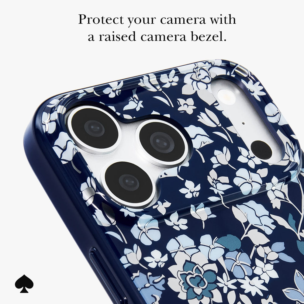 A close-up of a phone case with a navy blue background and a white and light blue floral pattern, featuring a raised bezel around the camera cutout. Text at the top reads 'Protect your camera with a raised bezel.
#color_flowerbed navy
