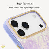 A close-up of a phone case with a lavender and white marbled pattern, featuring a raised gold bezel around the camera cutout. Text at the top reads 'Stay Protected' and 'Raised bezel to protect your camera. 
#color_blue pearl