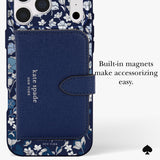 A navy blue Kate Spade New York phone case with a floral pattern border and a large textured magnetic wallet card holder on the back. The text on the right reads 'Built-in magnets make accessorizing easy.
#color_flowerbed navy
