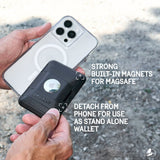 Black wallet with circular AirTag window attached via magnets to white iPhone 14 Pro with camera module visible.