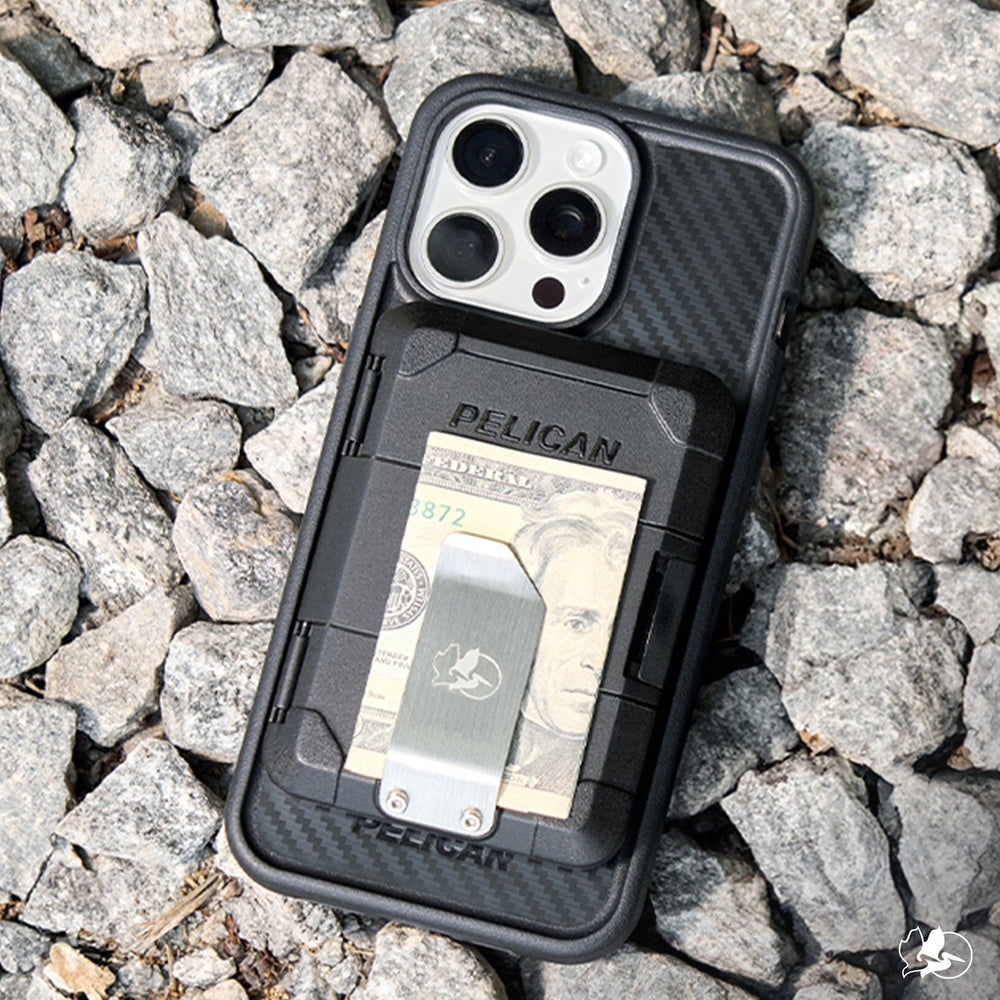 Black Pelican phone case with attached metal money clip holding cash cards, shown on rocky surface.