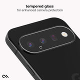 Close-up of the back of a black smartphone showing a raised camera surround with a clear tempered glass protector. Text at the top reads 'tempered glass for enhanced camera protection' on a light gray background.